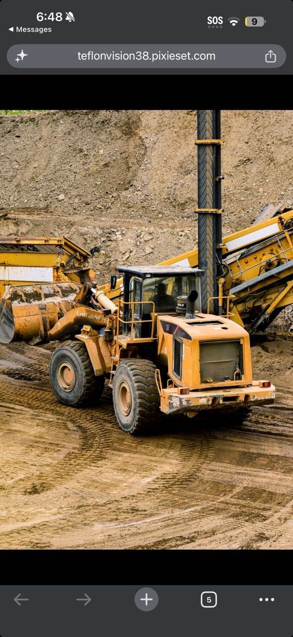 Wheel loader working beside mobile material processing equipment during aggregate production